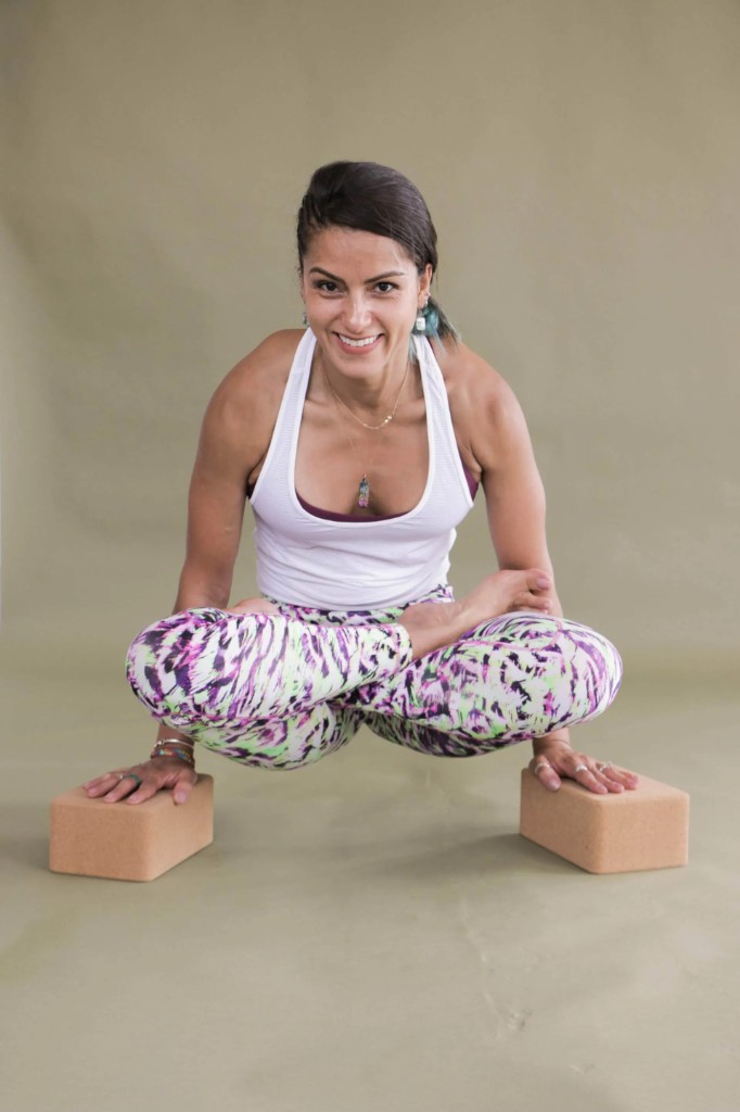 Kitia balanced on yoga blocks in a scale pose, smiling