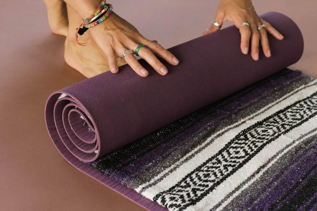 Hands rolling a purple yoga mat